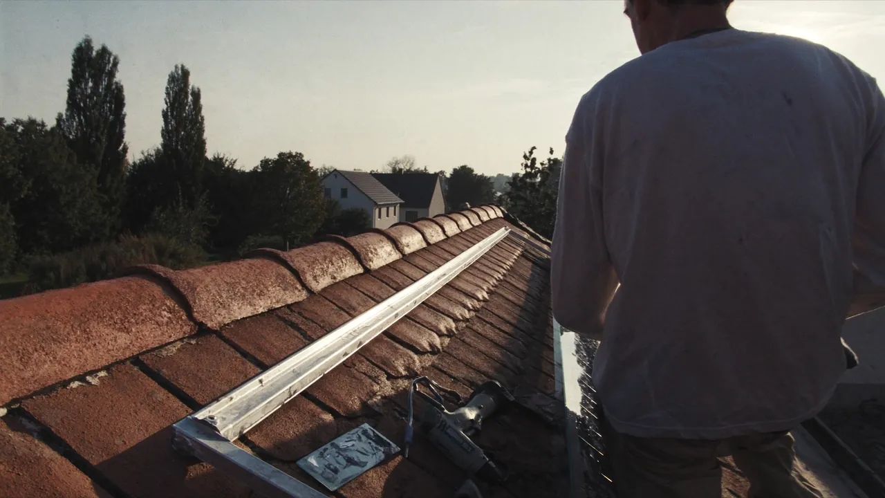 Dachdecker setzt auf dem Ziegeldach ein Solarmodul in die Montageschiene