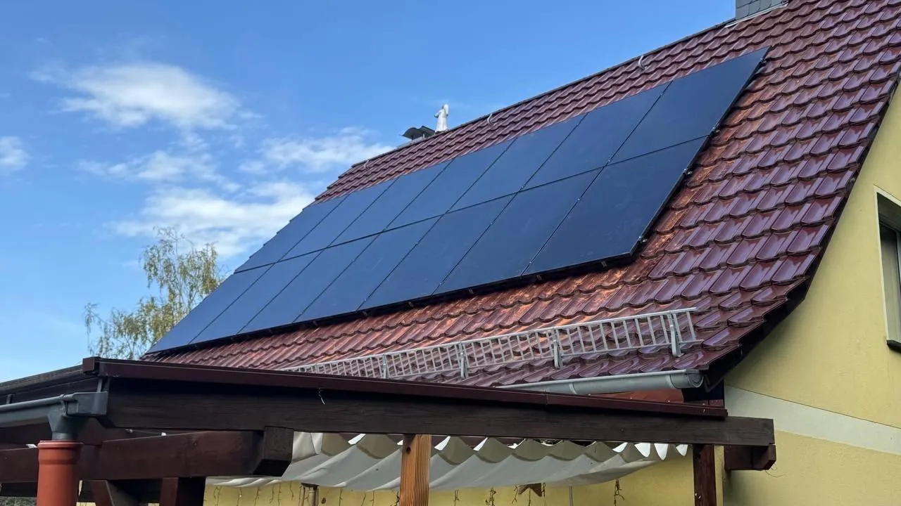 Ziegeldach mit Solarmodulen und Schneefanggitter über einer Pergola