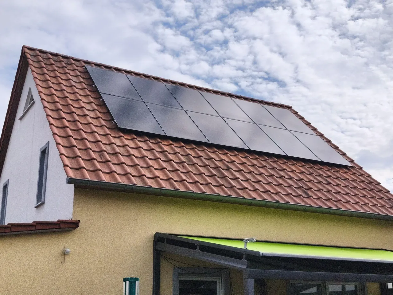 Satteldach mit roten Tonziegeln und schwarzen Solarmodulen