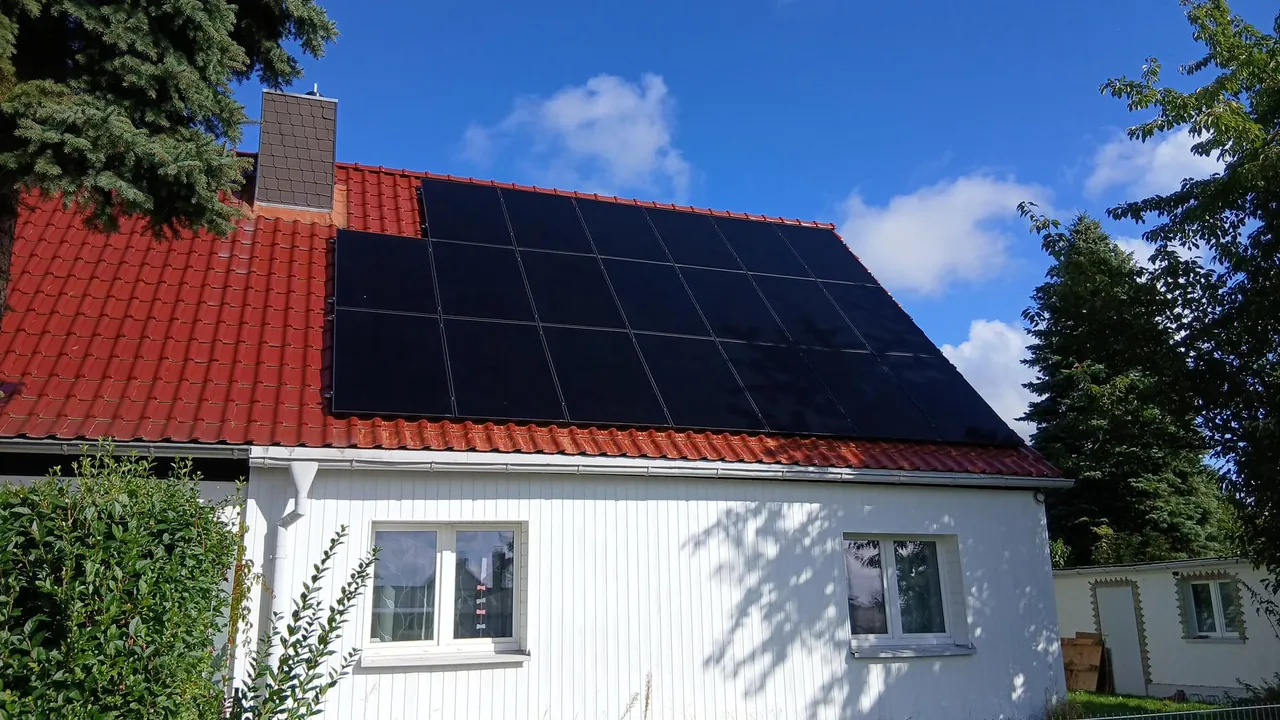 Einfamilienhaus mit rotem Ziegeldach und schwarzen Solarmodulen